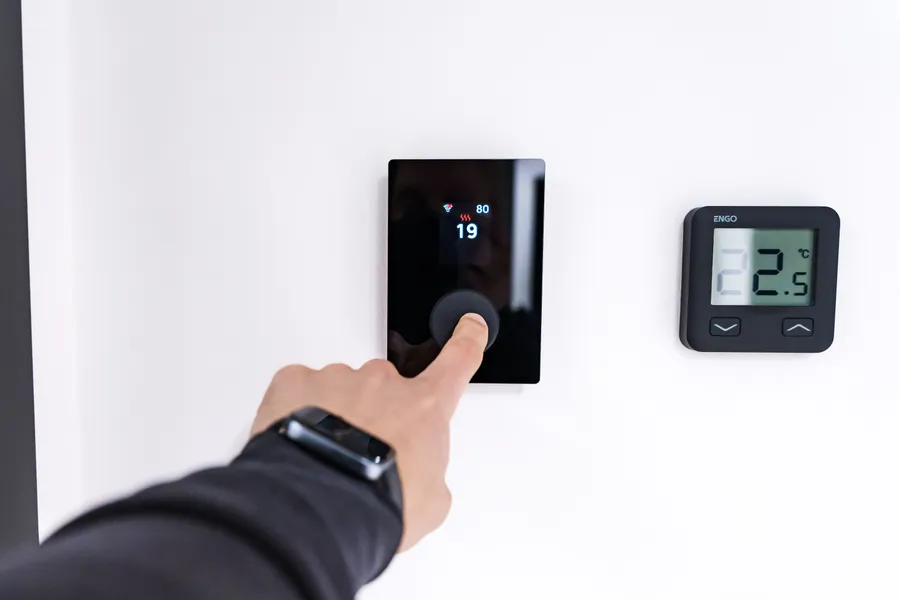 Hand adjusting a smart thermostat after installation